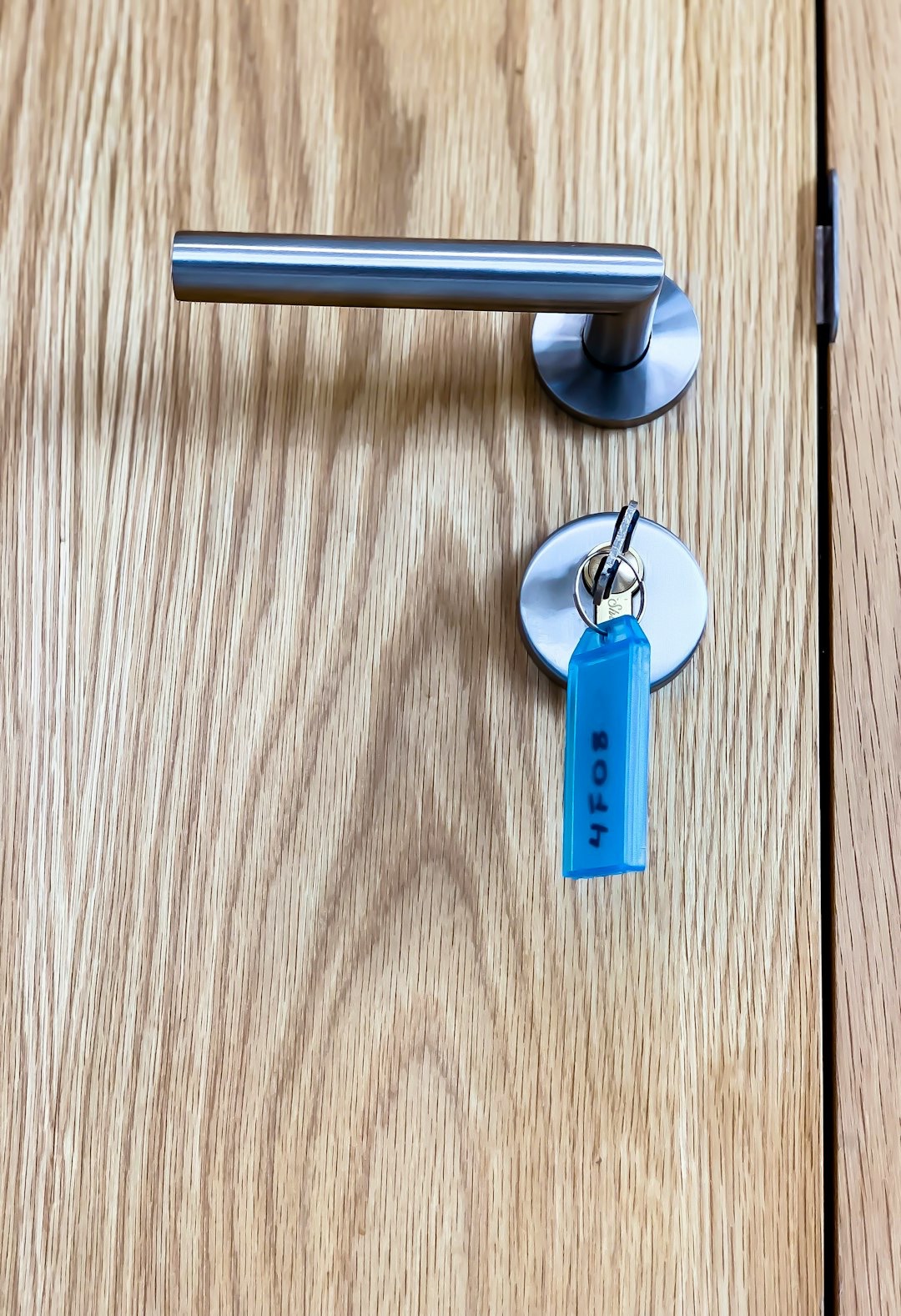 Hand inserting a key with blue fob into a modern door lock.